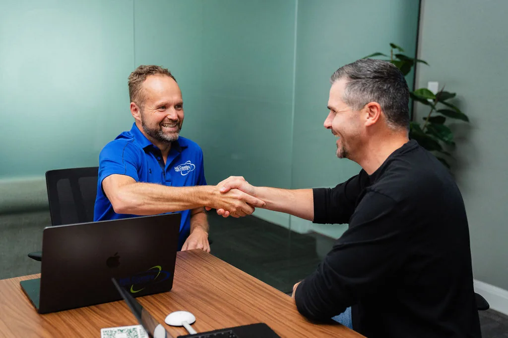 Two people shaking hands across the conference table at Corridor Collective
